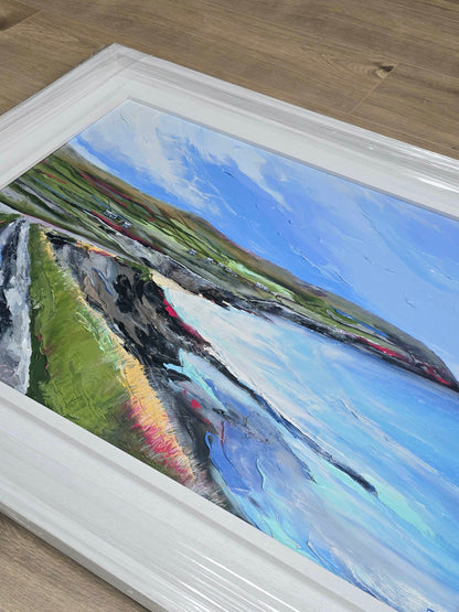 Framed painting of a landscape with a river and mountains on a wooden floor.