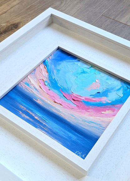 Framed abstract coastal painting with blue and pink hues