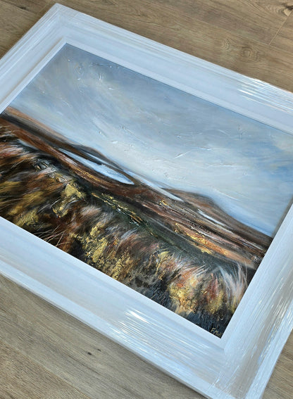 Framed artwork of a landscape with mountains and a sky.