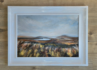 Framed painting of a landscape with a lake on a wooden surface