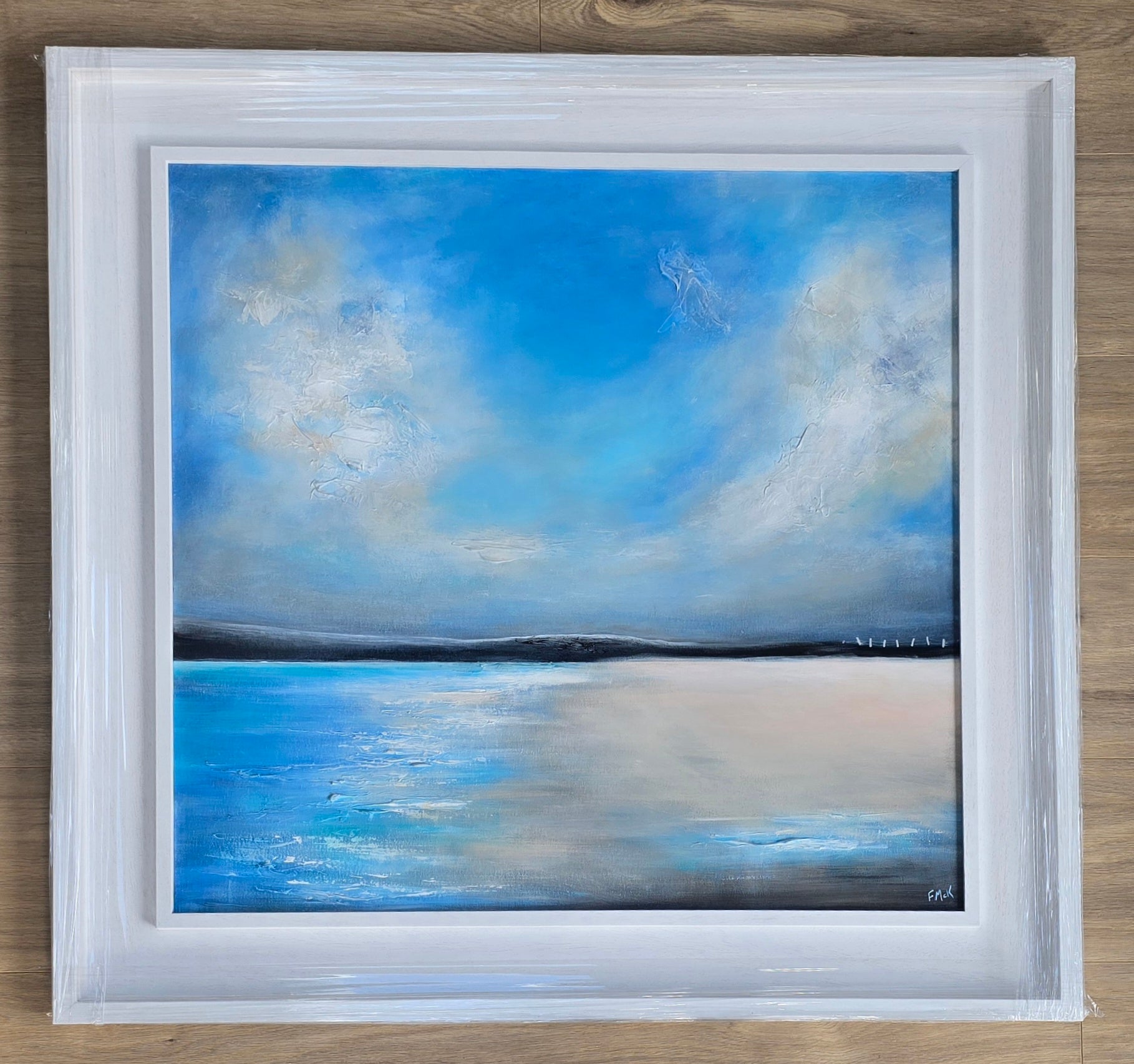 Framed painting of a blue sky with clouds over water