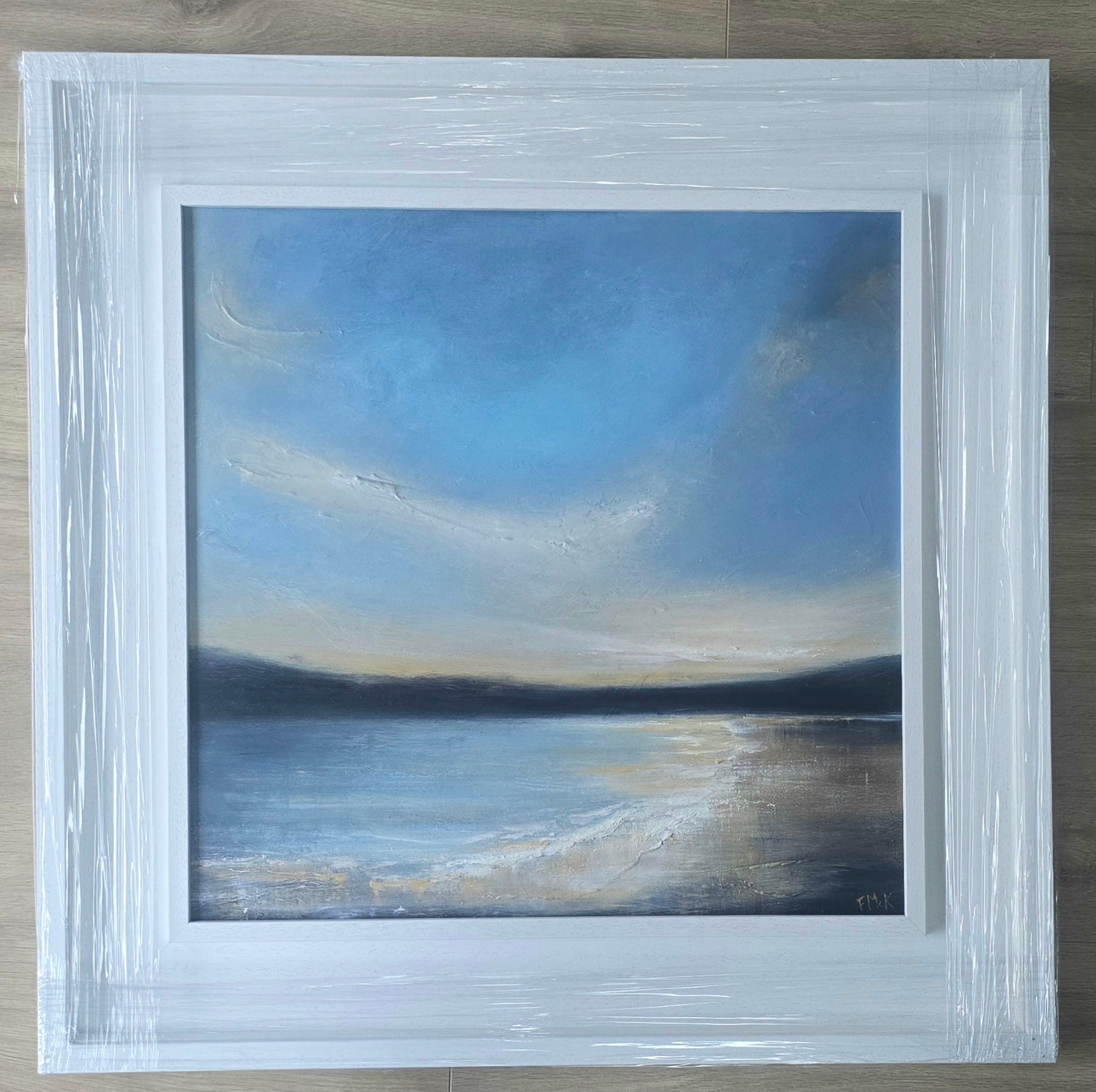 Framed painting of a landscape with a blue sky and water.