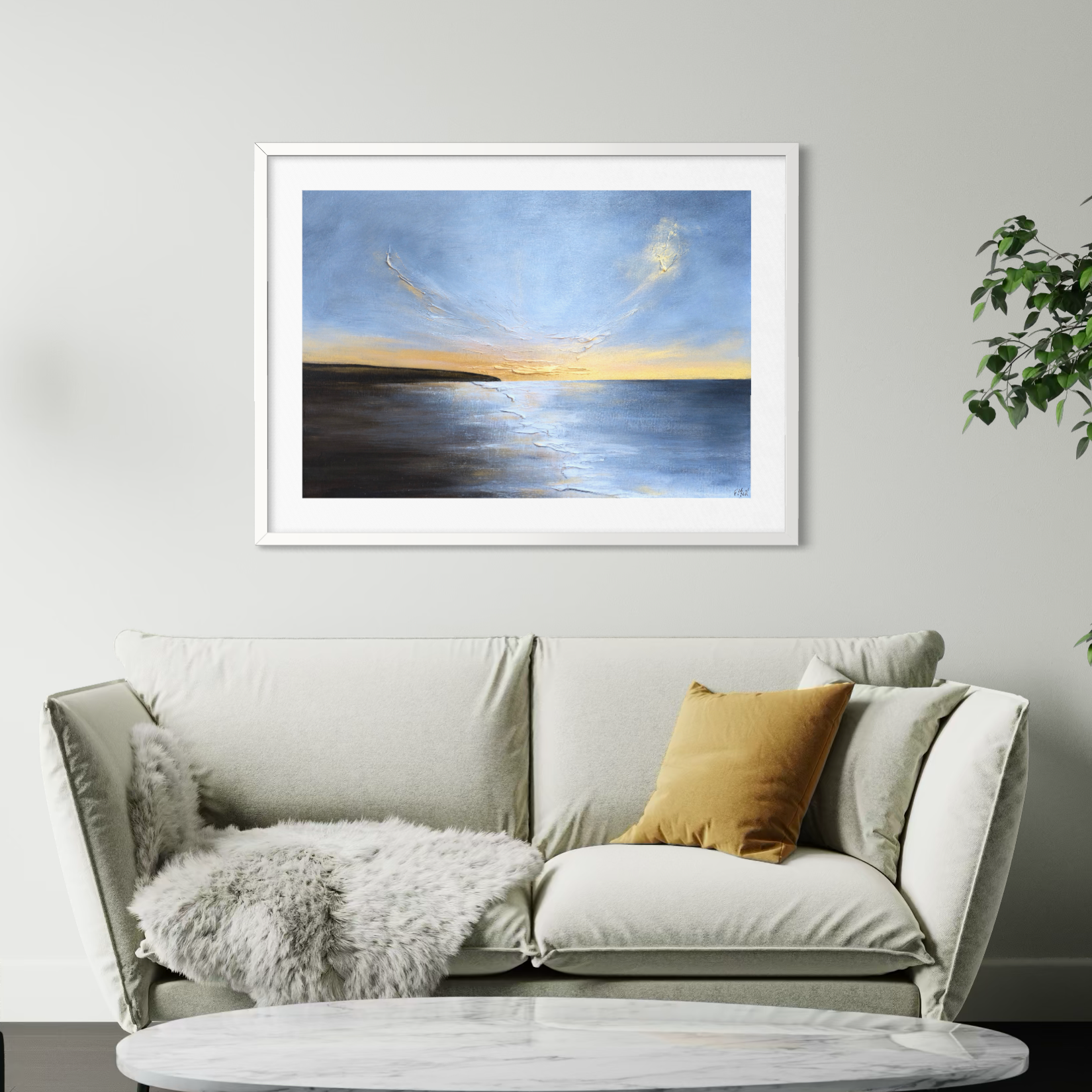 Framed artwork of a sunset over water on a wall above a sofa.