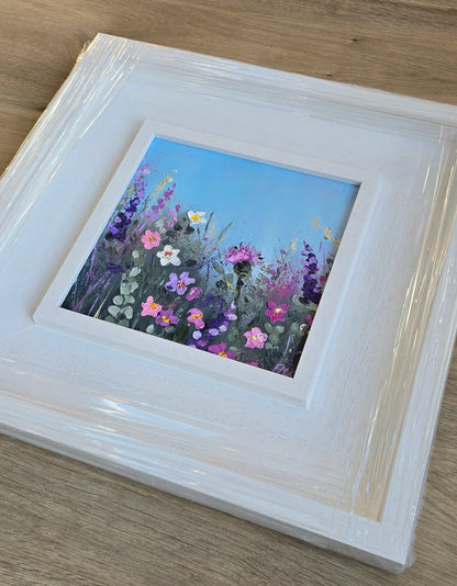 Framed painting of wildflowers on a wooden surface