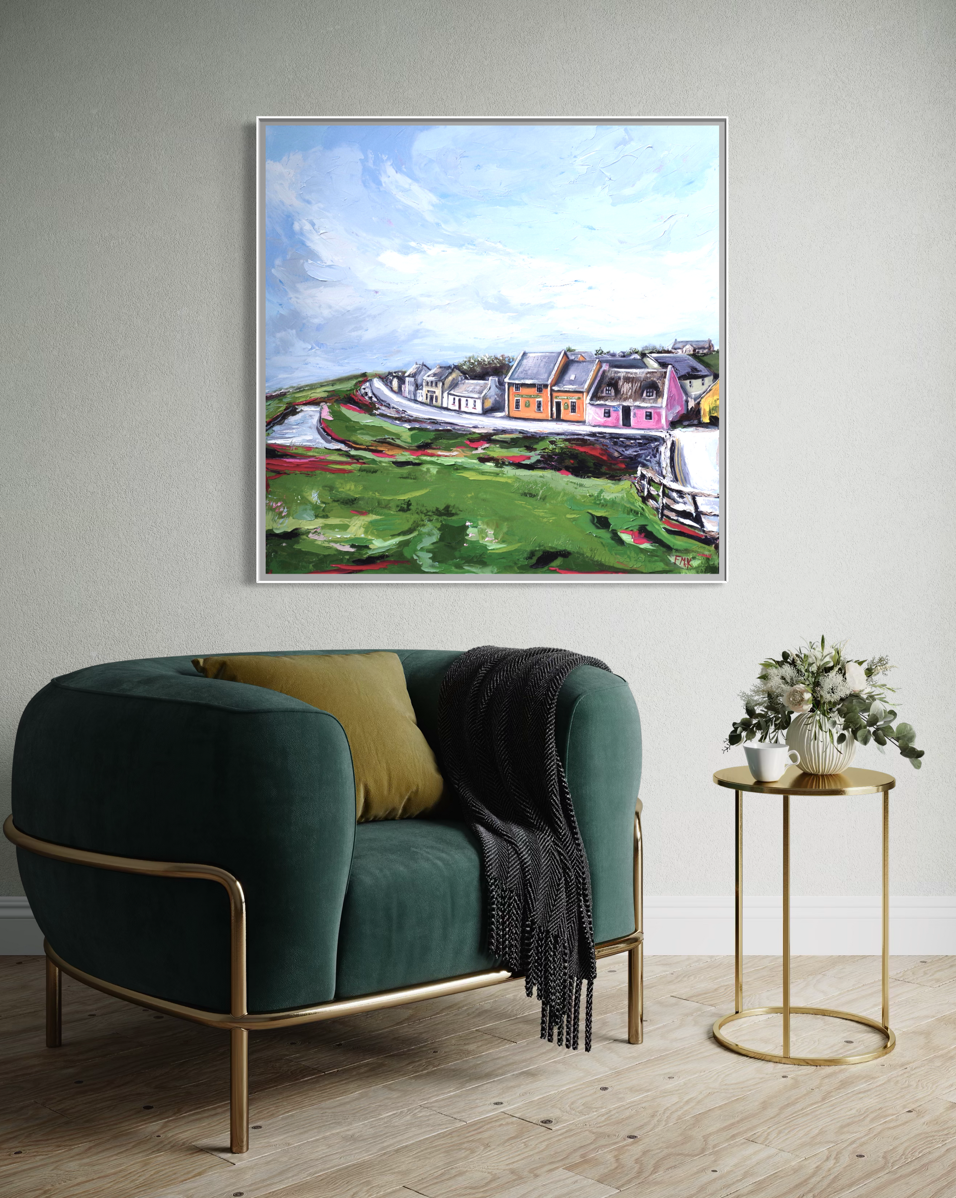 Framed artwork of a colorful landscape above a green armchair in a room.