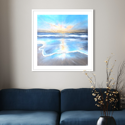 Framed artwork of a beach scene with a blue couch and decorative plant in the foreground.