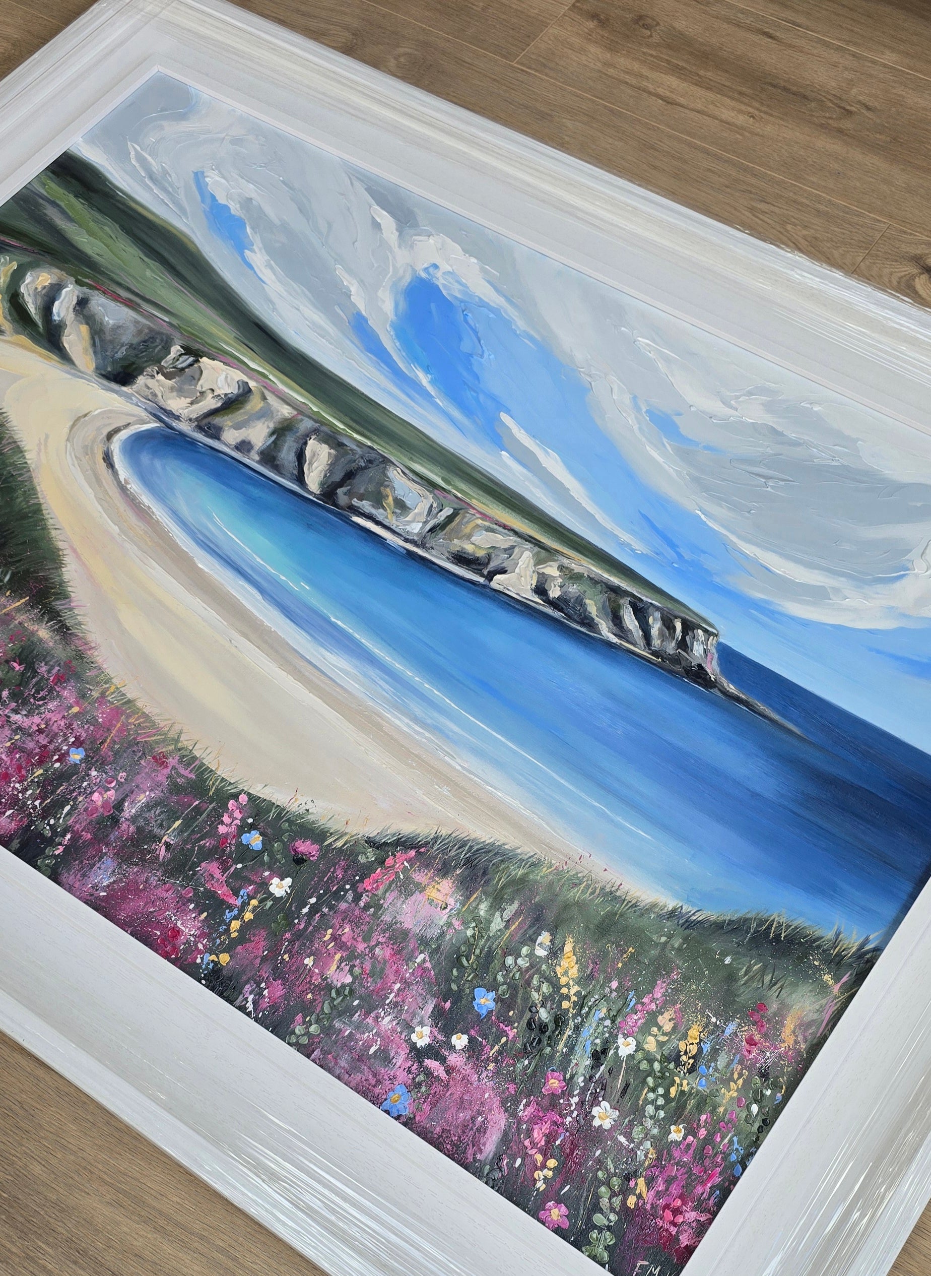 Framed artwork of a coastal Donegal scene with flowers.