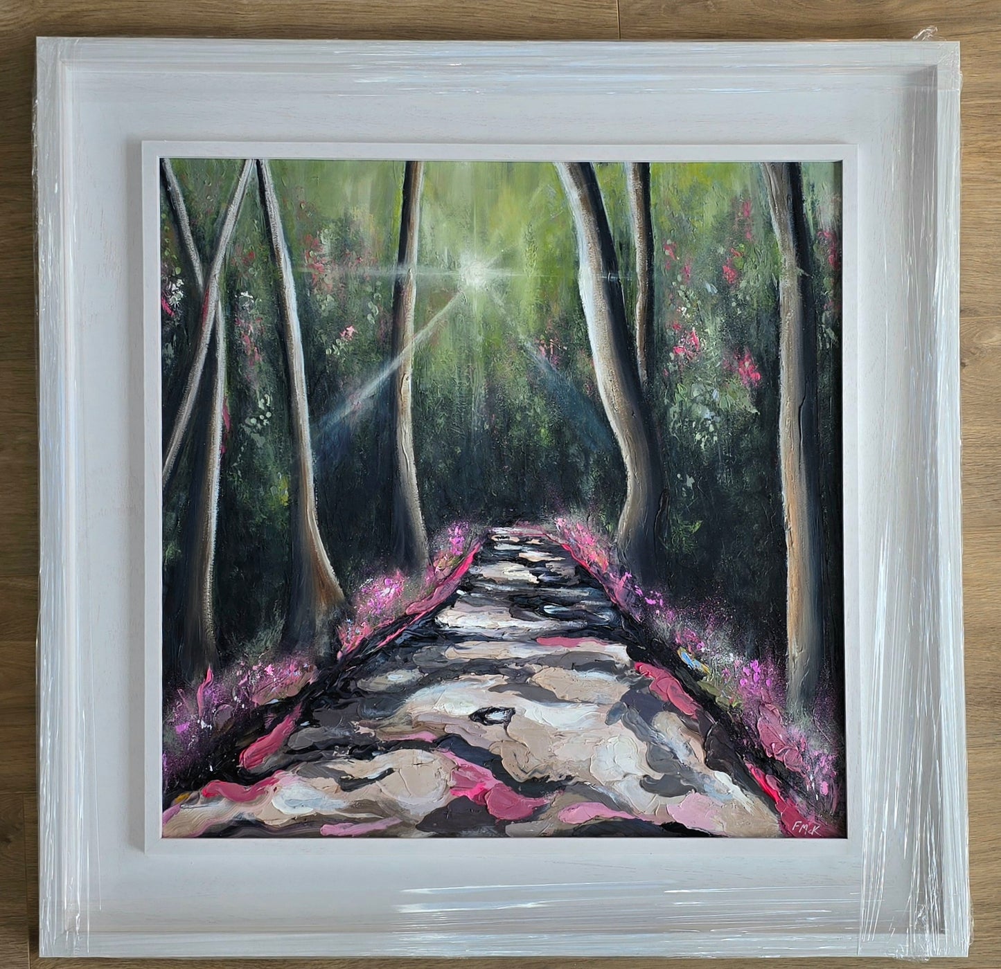 Framed painting of a forest path with sunlight filtering through the trees