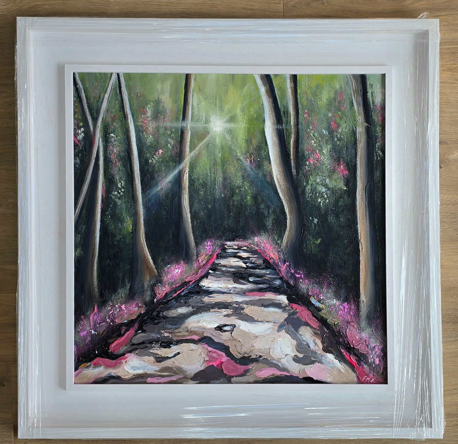 Framed painting of a forest path with sunlight filtering through the trees