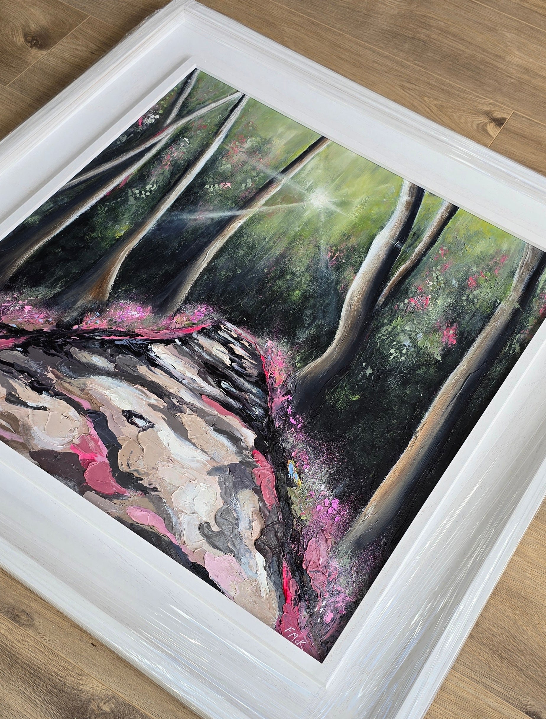Framed painting of a natural scene with trees and pink flowers
