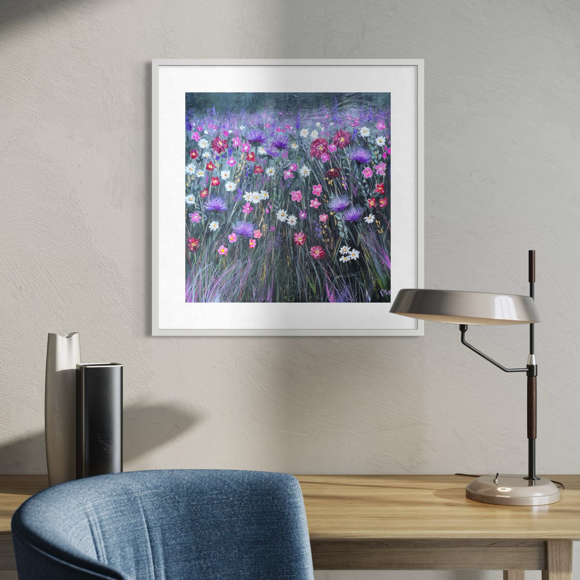 Framed artwork of a floral scene on a wall above a desk with a lamp and chair.