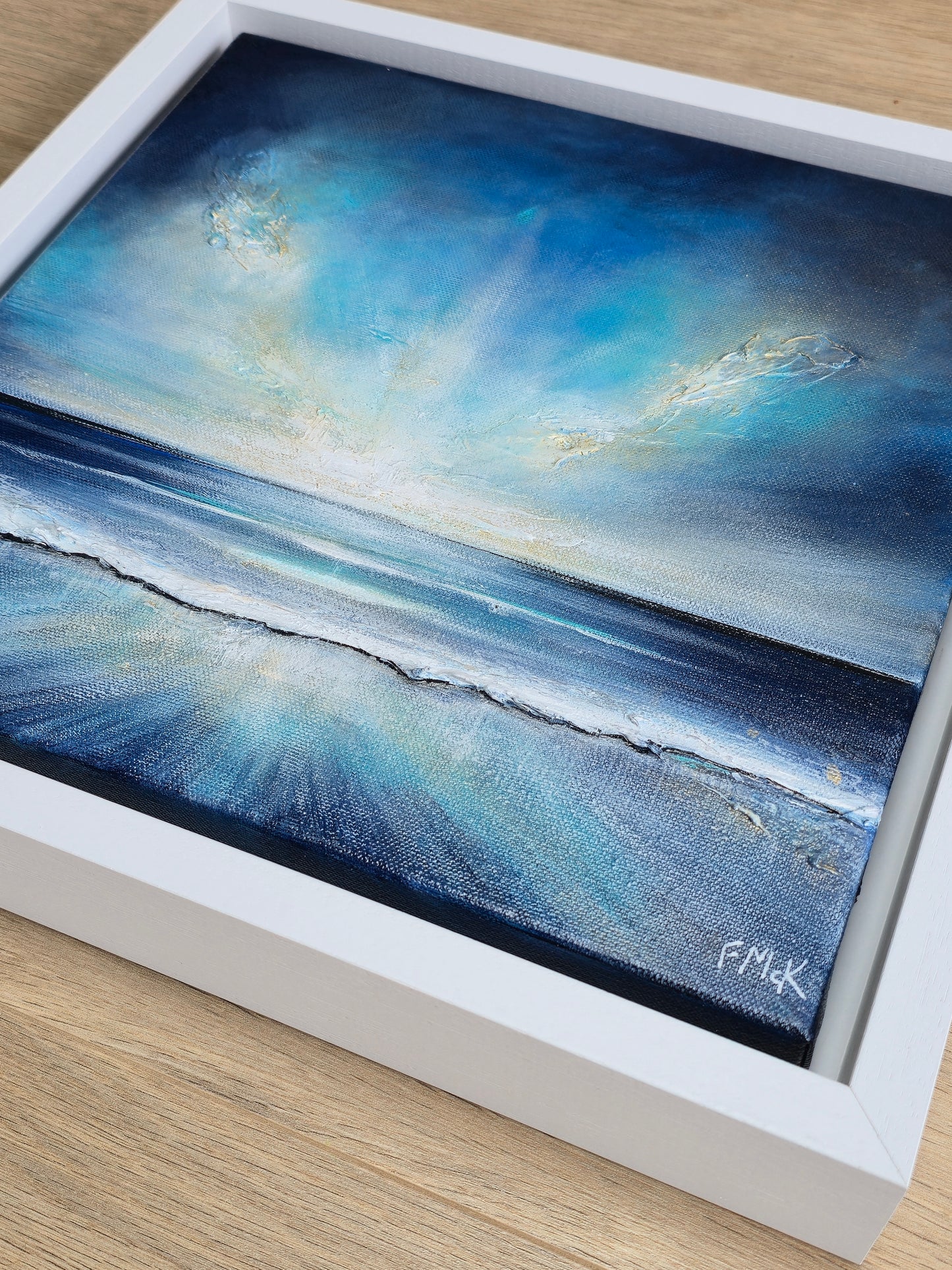 Framed artwork of a blue ocean scene with a white frame.