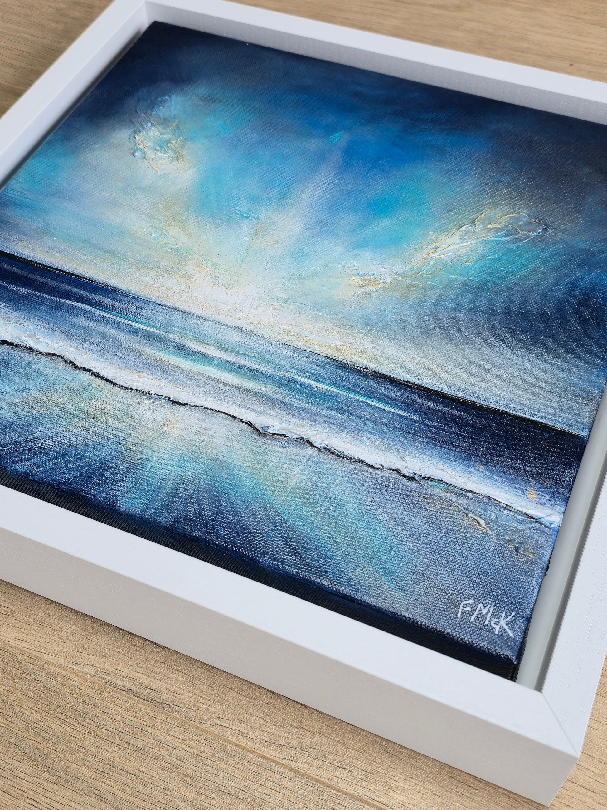 Framed artwork of a blue ocean scene with a white frame.