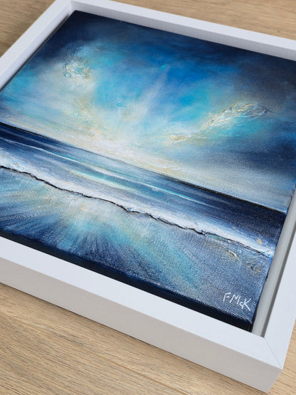 Framed artwork of a blue ocean scene with a white frame.