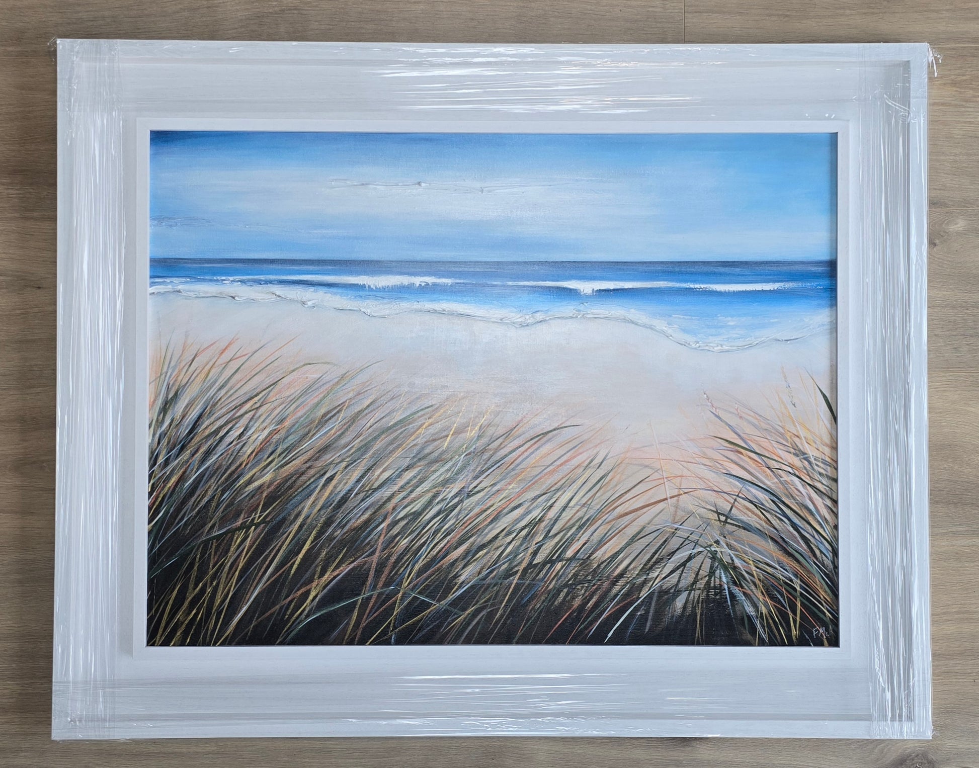 Framed artwork of a beach scene with grasses and ocean.