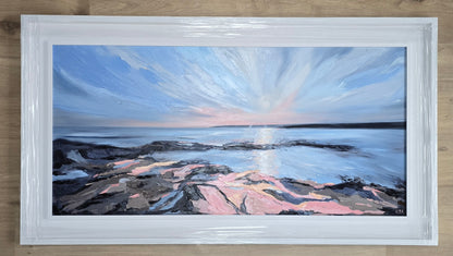 Framed painting of a coastal scene with a blue sky and rocky shore.