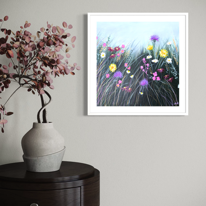 Framed artwork of flowers on a wall above a vase with pink flowers.